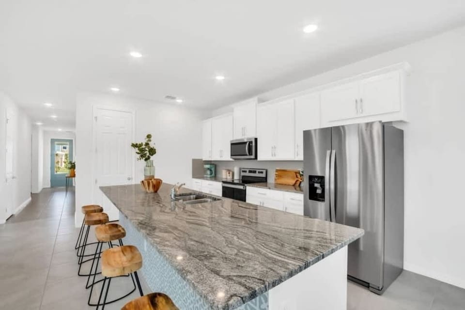 - Full kitchen with island seating stainless appliances and space
- Open kitchen ideal for cooking group meals and longer stays
- Airbnb kitchen with fridge oven bar stools and modern layout

