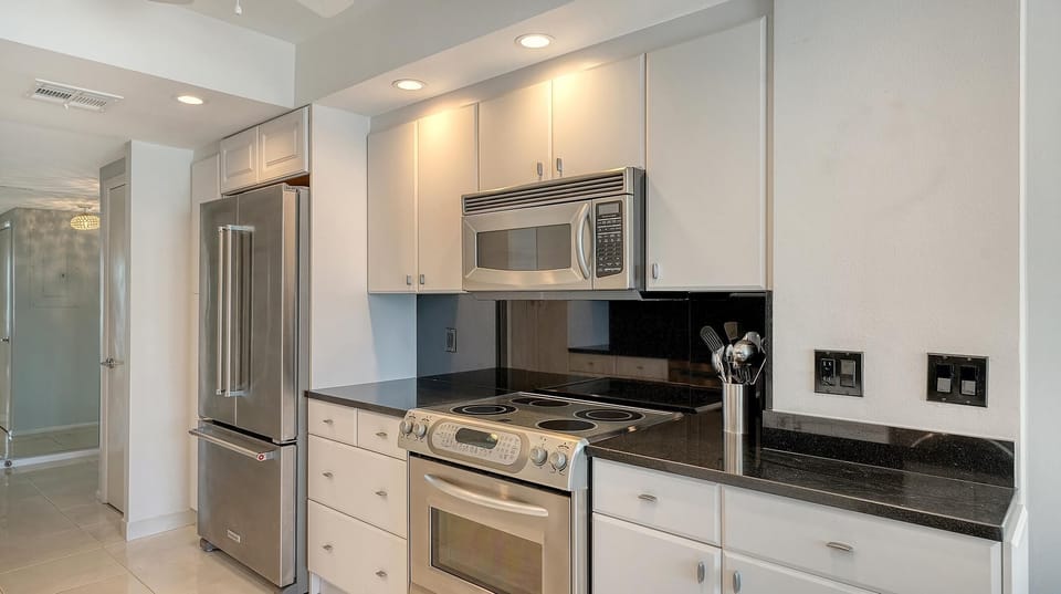 Stainless steel appliances and black granite countertops line the white cabinetry in the kitchen.