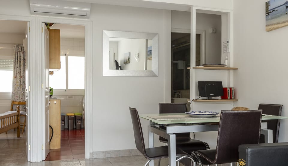 Bright dining area with a glass table and direct access to the kitchen and the other rooms of the apartment.