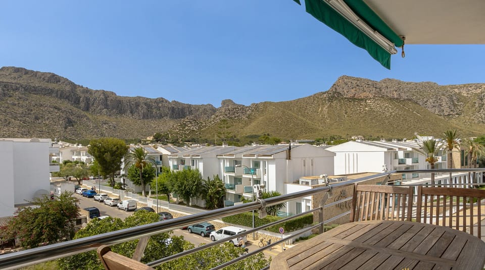 Furnished balcony with table and chairs offering open mountain views in Port de Pollença.