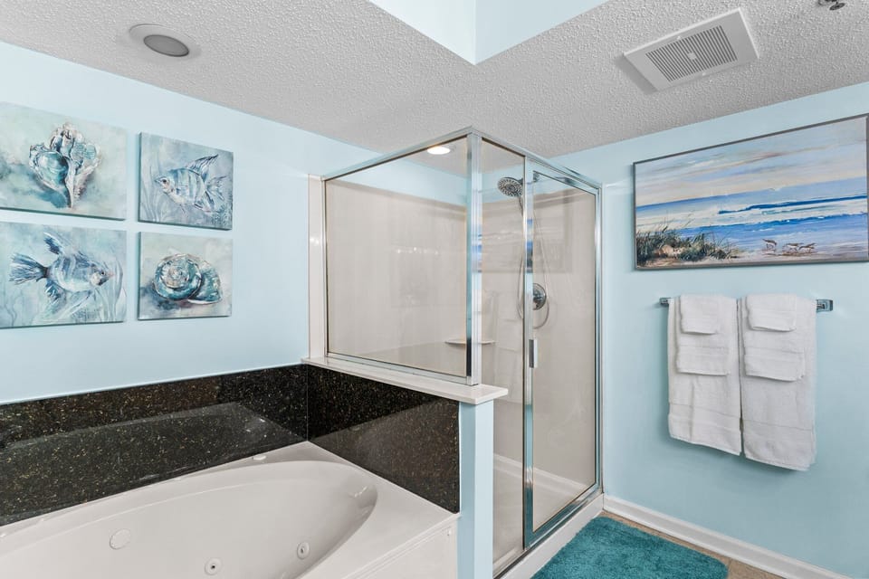 Glass shower and a jetted tub in the light blue bathroom at Crescent Shores 402, a Crescent Beach rental