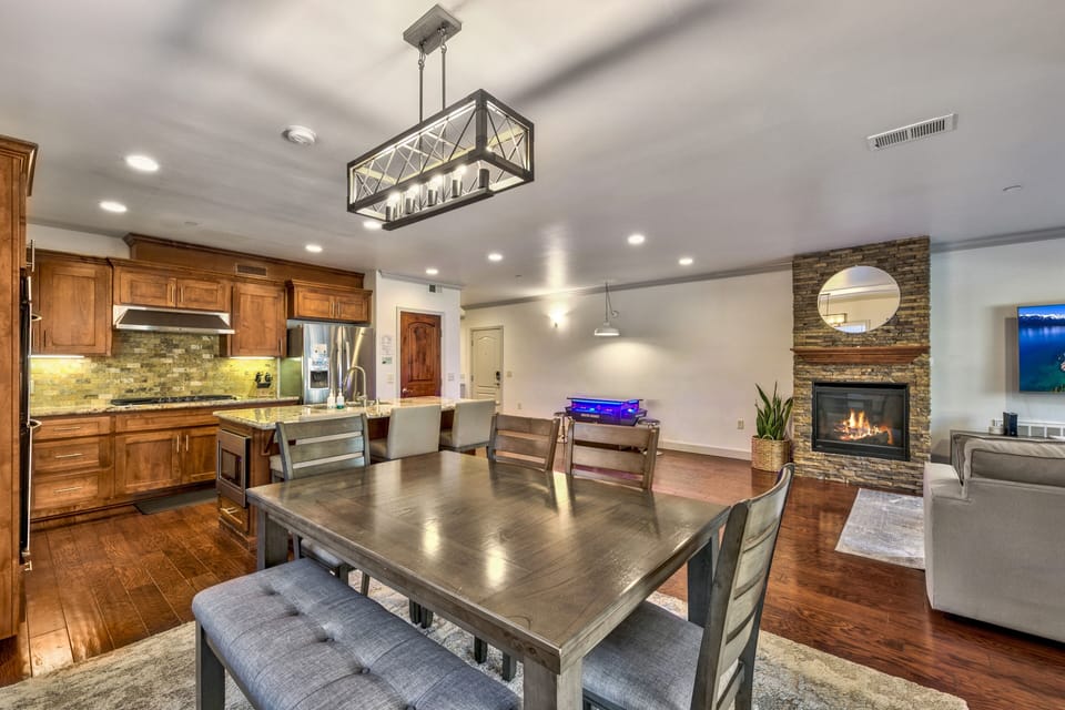 Gather around your spacious dining table where warm wood meets elegant stone, creating the perfect setting for memorable meals.