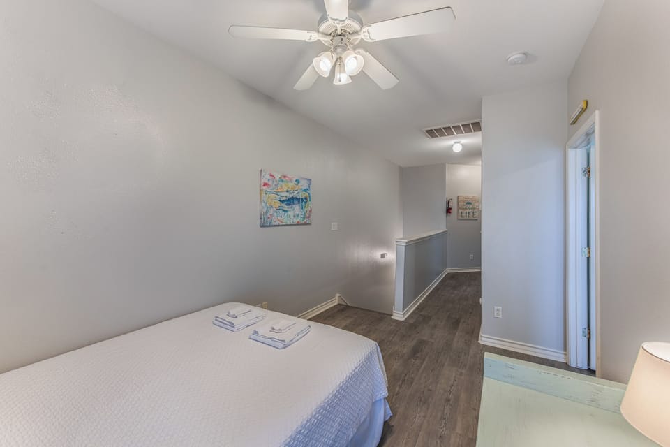 Your serene bedroom features a comfortable bed with fresh towels, ceiling fan for optimal comfort, and modern hardwood floors.