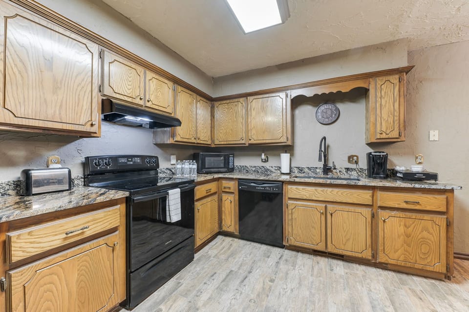 Furnished kitchen supplied with dishes, cutlery, and appliances. 