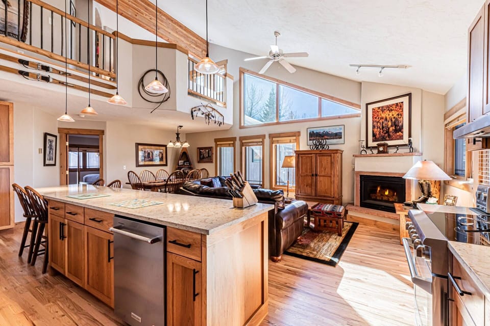 Bright and airy open-concept kitchen and living space with vaulted ceilings, rustic wood finishes, and a cozy fireplace for mountain lodge vibes.
