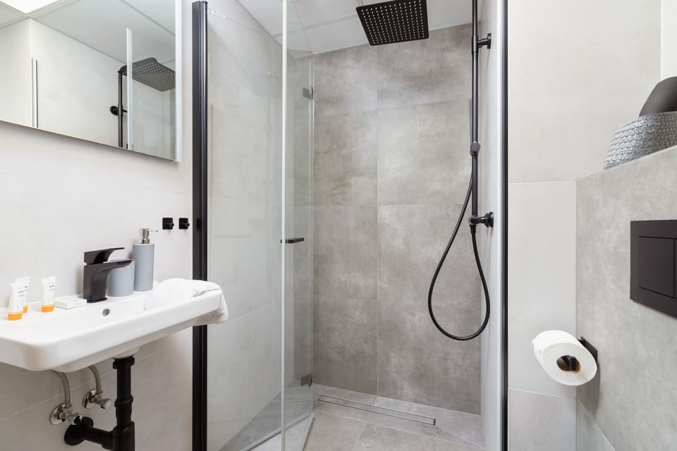 A modern bathroom with minimalist gray tiles and a walk-in shower.