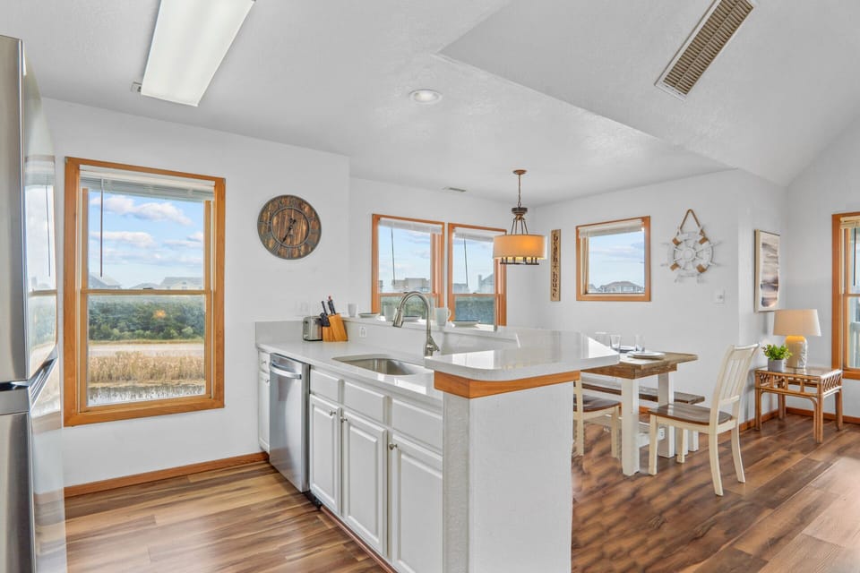A pristine, white kitchen featuring a sleek breakfast bar, blending style and functionality effortlessly.