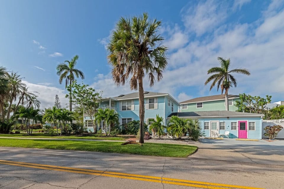 Siesta Key Beach Retreat with pink door, pastel charm, and tropical landscaping—your cheerful welcome to island living just steps from the shore