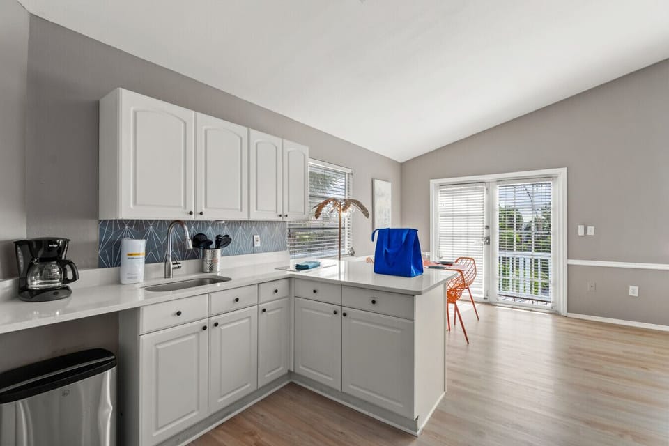 Siesta Key Beach kitchen with geometric backsplash, orange dining, and glass-top table under natural light.