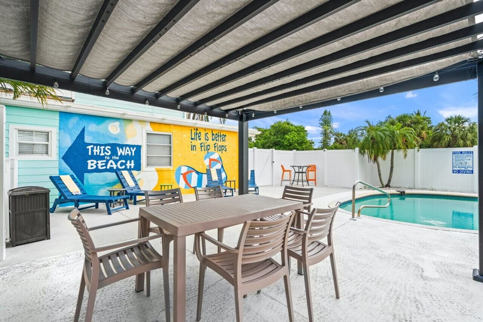 Siesta Key Beach poolside dining featuring shaded seating, tropical ambiance, and playful flip-flop mural charm—crafted for breezy meals and seaside relaxation.
