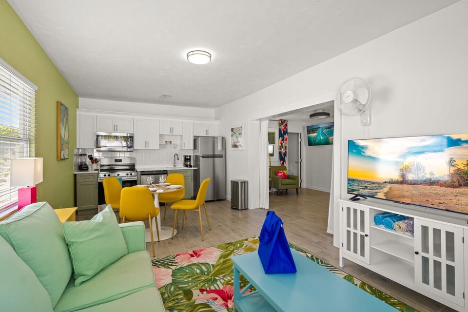 Siesta Key Beach open-concept living with pastel couch, yellow dining chairs, and tropical accents for vibrant coastal comfort