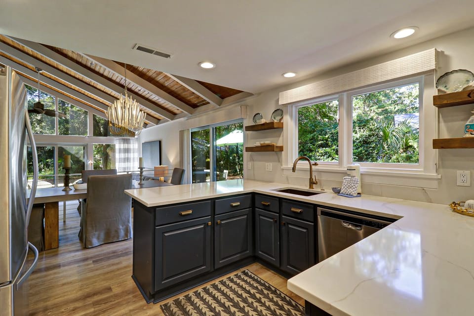 Kitchen open to dining and living area, views of side yard and pool