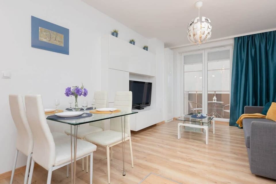 An open-plan space with a dining table set for two and a cozy living area in the background, emphasizing comfort and practicality.
