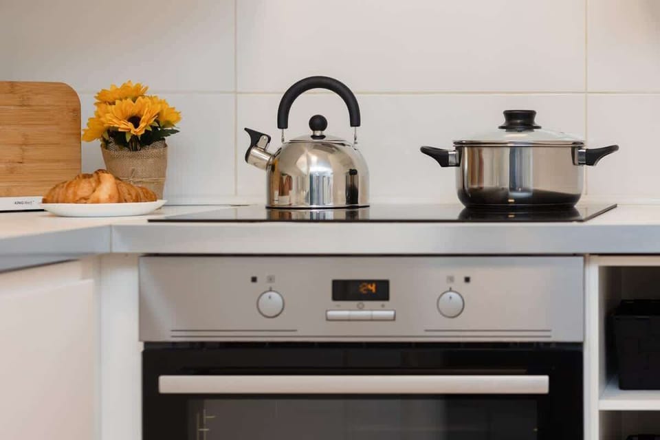 A detailed shot of the kitchen oven with a modern design, including a kettle and utensils on the stove.