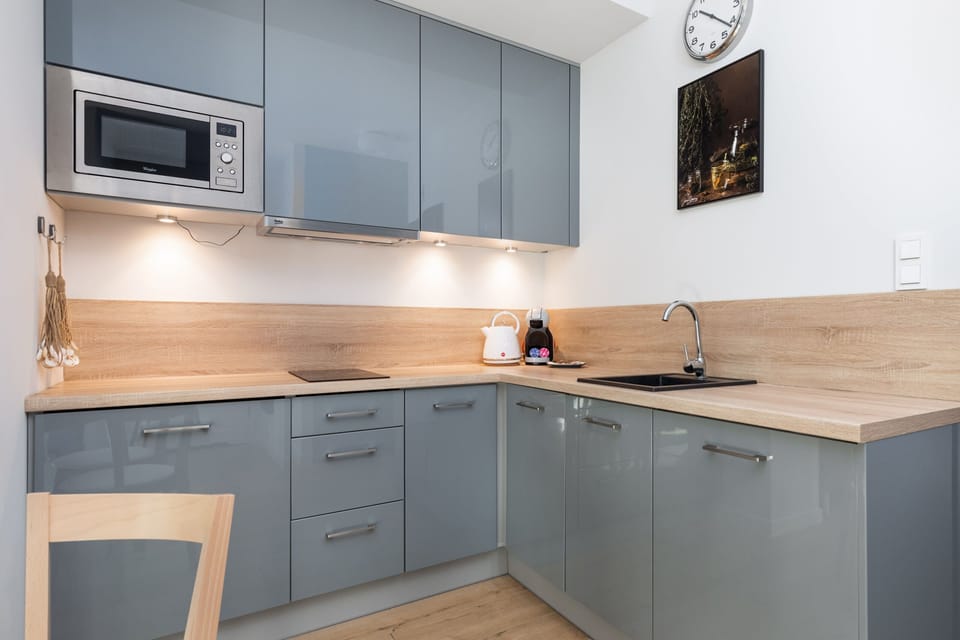 A modern kitchen with gray cabinetry, wood countertops, and built-in appliances, designed for efficiency and style.