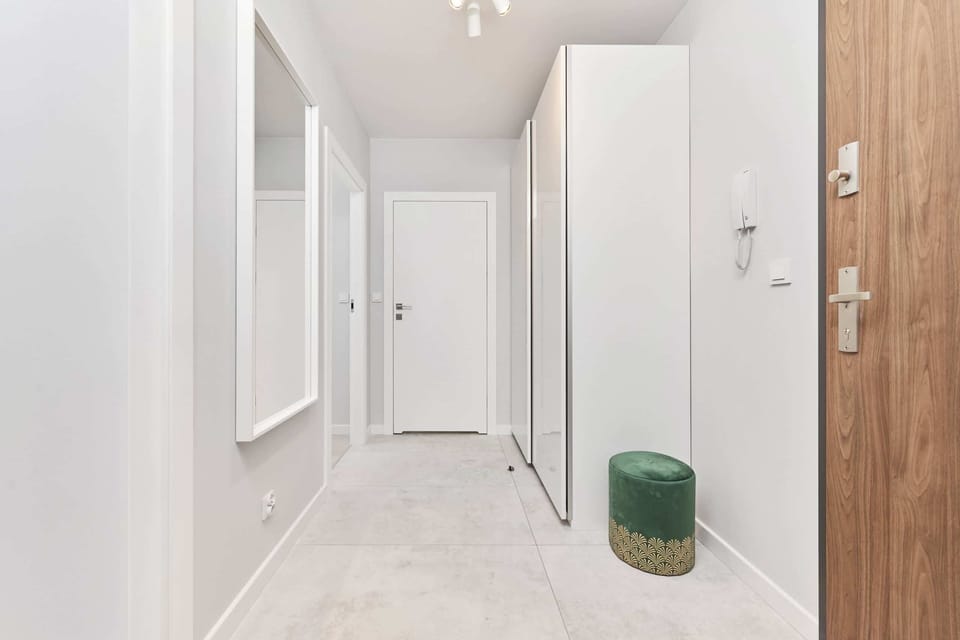 Spacious hallway with a full-length mirror and green velvet ottoman providing a luxurious welcome to the apartment.