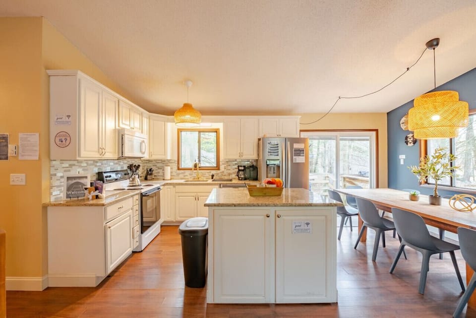 Modern kitchen with white cabinets, granite, stainless steel, and dining area.
