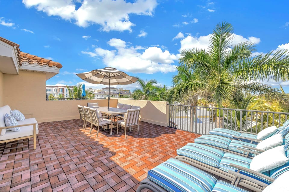 Rooftop terrace with chaise lounge chairs, outdoor dining for eight with view overlooking the palms.