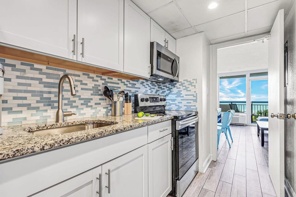 Modern kitchen with sleek cabinetry and a stylish blue-tile backsplash, fully equipped for your culinary needs. Just steps from the bedroom, this space offers convenience and functionality, allowing you to enjoy meals with a stunning ocean view.