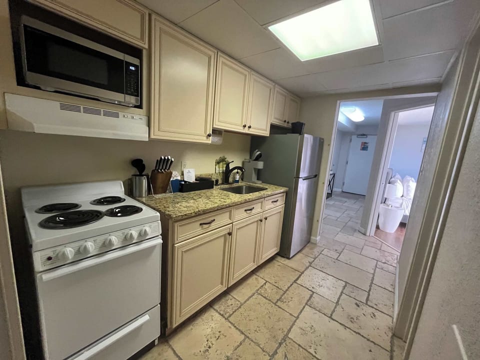 Convenient kitchen area featuring a full-size fridge, stove, microwave, sink, and easy access to the living space.