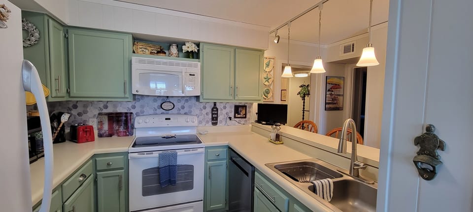View of well lit kitchen and breakfast bar, and small TV