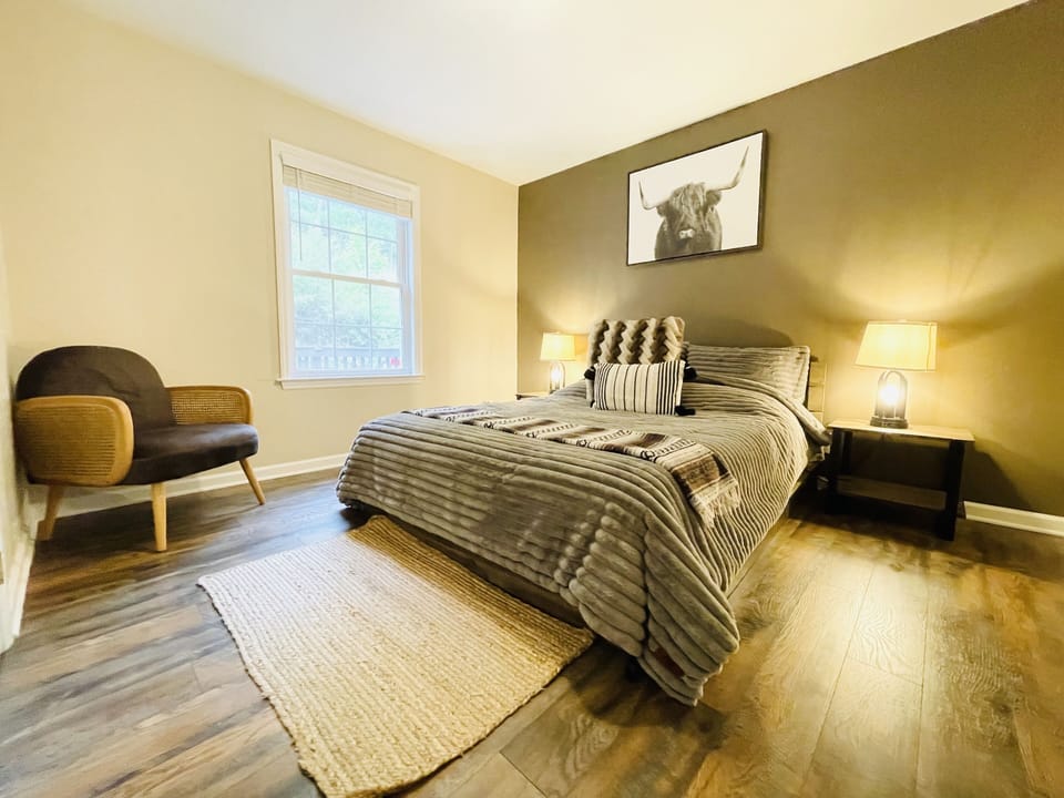 Queen size guest bedroom with a modern arm velvet lounge comfy chair. 