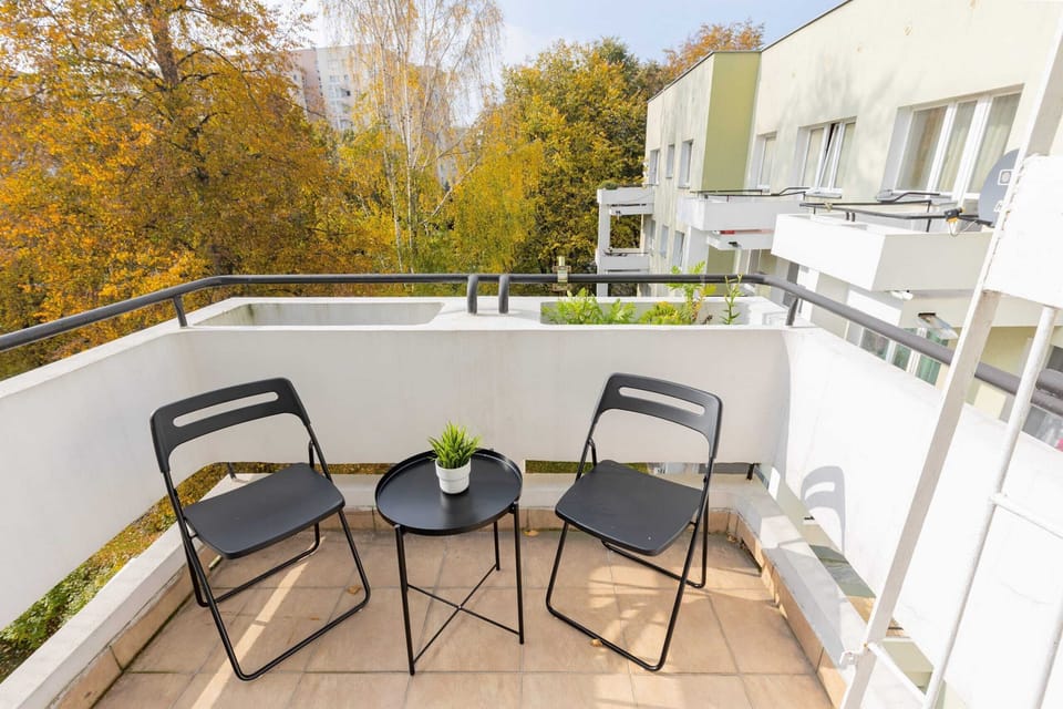 A spacious balcony with chairs and a small table, perfect for enjoying a coffee while overlooking the greenery.