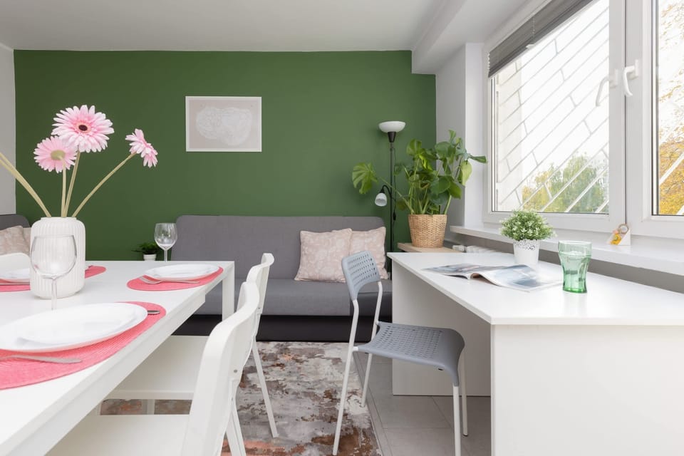 A stylish living room with a green feature wall, a comfortable sofa, and a coffee table, complemented by natural light.