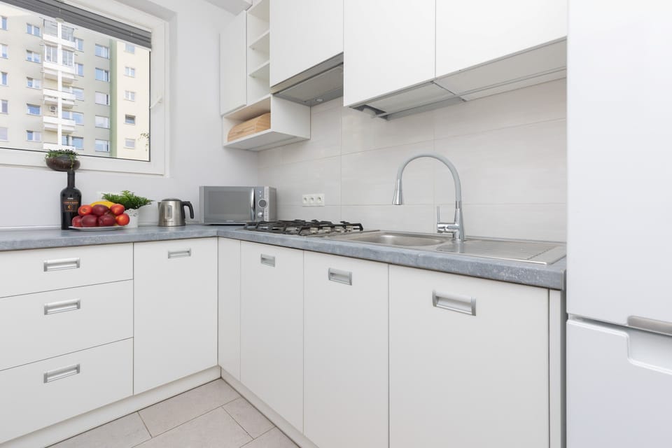 A well-organized kitchen with white cabinets, sleek countertops, and modern appliances, including a built-in oven.