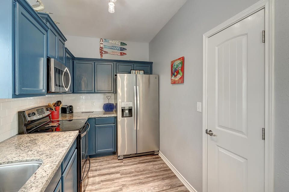 Cook your favorite meals in this fully equipped kitchen featuring granite countertops, stainless steel appliances, and charming blue cabinetry.