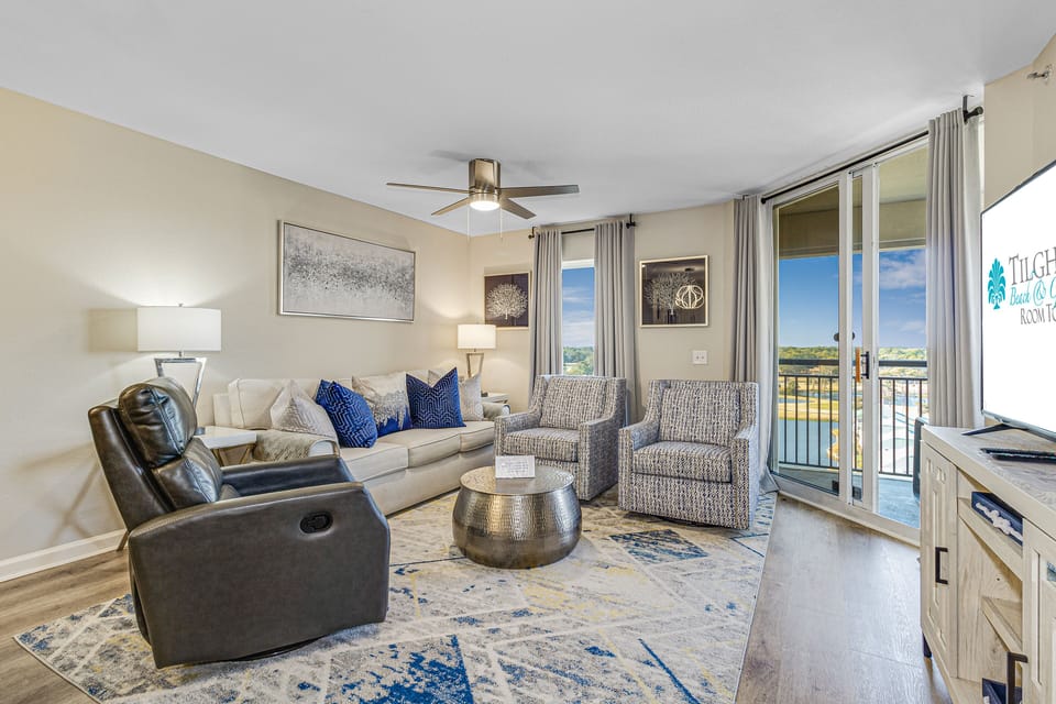 Sink into plush seating with blue accent pillows while enjoying natural light from your private balcony in this inviting living space.