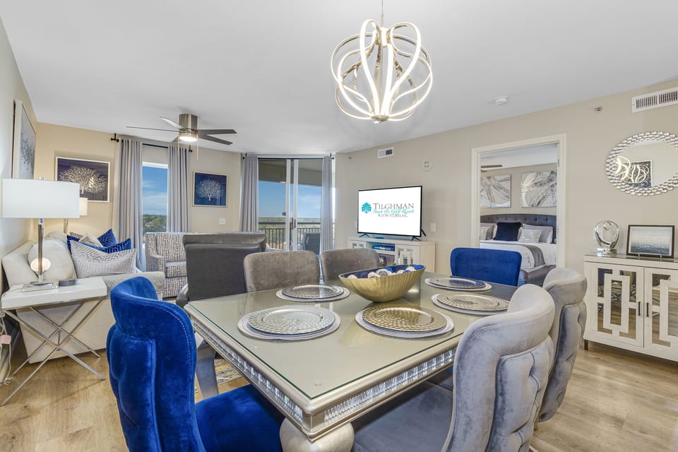 Elegant open-concept living with stylish navy accents, modern chandeliers, and scenic balcony views for your perfect getaway.