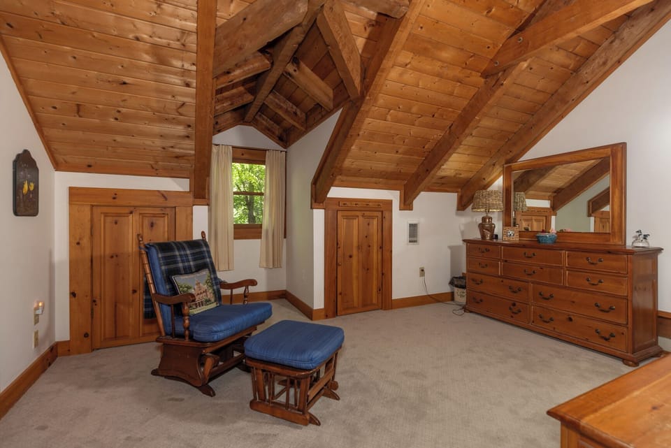 Unwind in your private retreat with soaring wood-beamed ceilings and a cozy glider chair, where rustic charm meets mountain serenity.