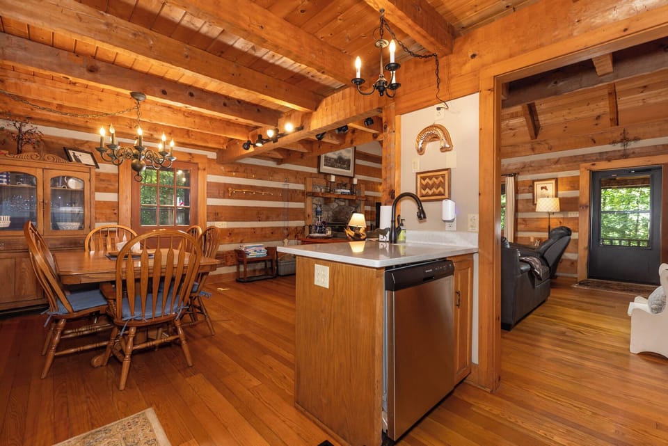 Relax in your open-concept cabin with vaulted wood ceilings, a fully equipped kitchen island, and a cozy dining area perfect for gathering after a day of adventure.