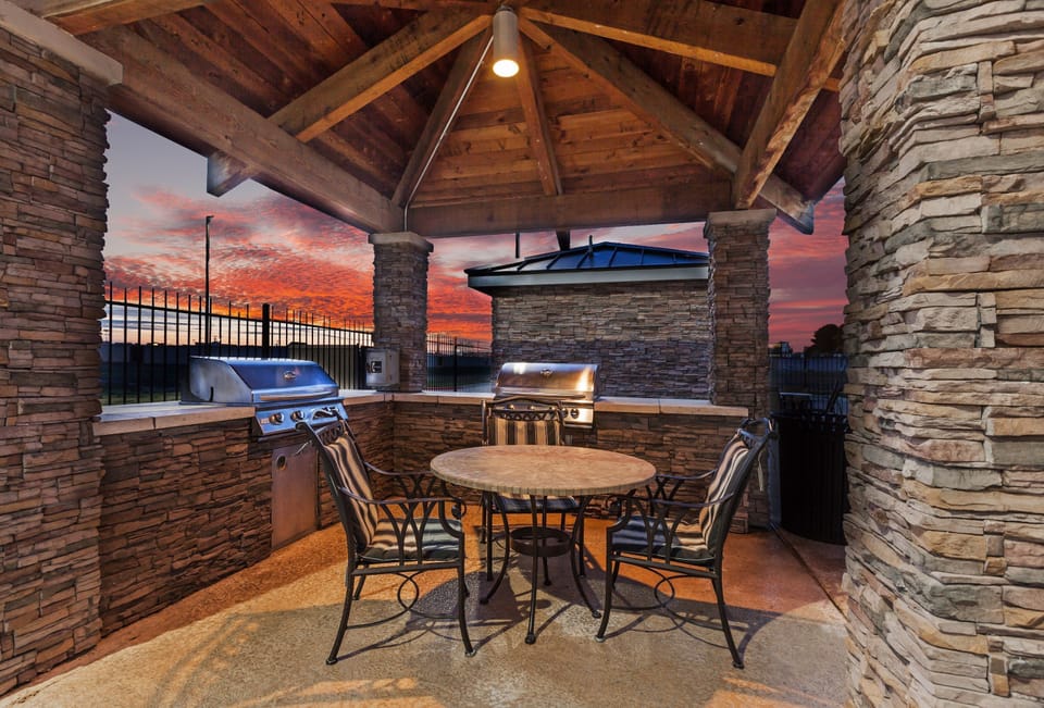 Outdoor grilling area with a table and sunset sky.