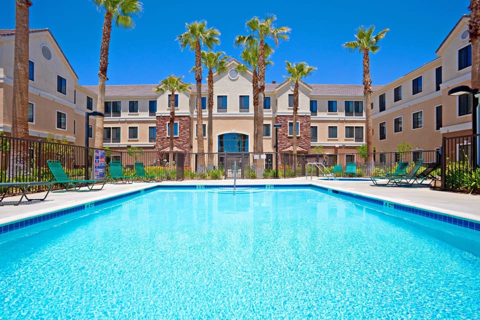Heated outdoor pool surrounded by palm trees and lounge chairs.