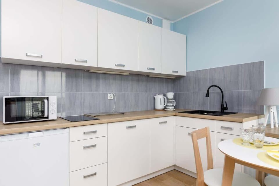 A modern kitchen with white cabinetry, a tiled backsplash, and sleek appliances for a functional design.
