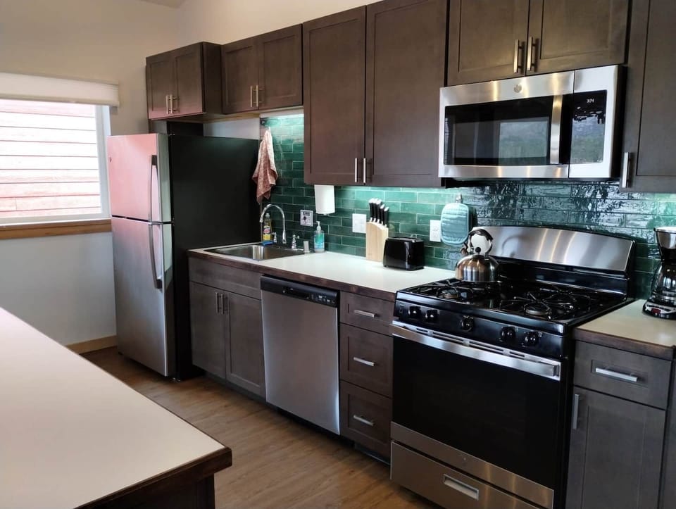 Alderwood Cabin Kitchen - Equipped with Residential Fridge, 12-Cup Drip Coffee Maker, Toaster, Microwave, 4-burner stove with Oven, Tea Kettle, Coffee, Creamer, Sugar, Tea, Filters, and Basic Cooking Essentials.