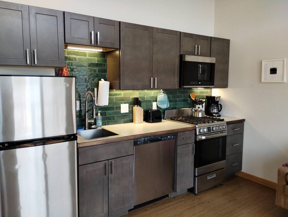 Dockside Cabin – Kitchen Equipped with Fridge, Dishwasher, 12-Cup Drip Coffee Maker, Toaster, Microwave, 4-burner stove with Oven, Tea Kettle, Coffee, Creamer, Sugar, Tea, Filters, and Basic Cooking Essentials.
