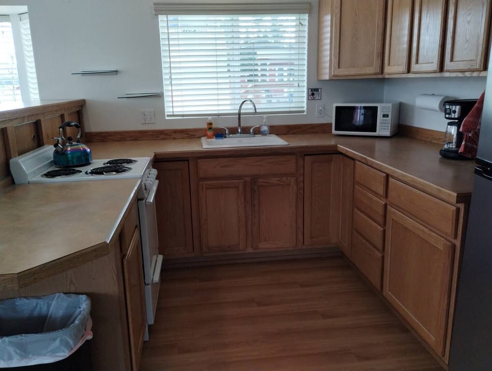 Waterfront Cabin – Kitchen Equipped with Fridge, 12-Cup Drip Coffee Maker, Toaster, Microwave, 4-burner stove with Oven, Tea Kettle, Coffee, Creamer, Sugar, Tea, Filters, and Basic Cooking Essentials.