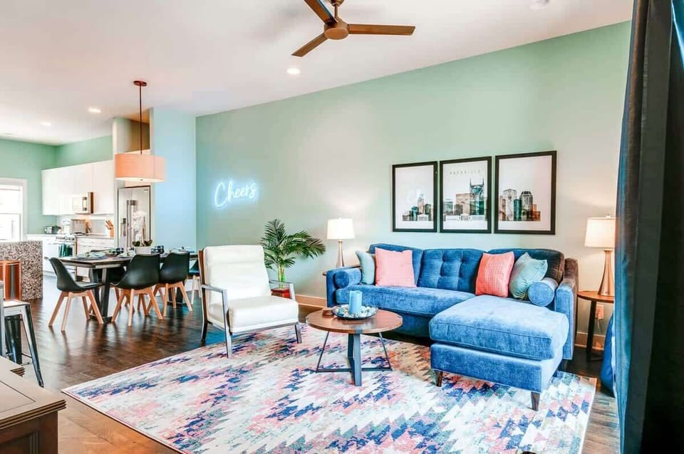 Living room with sectional seating and the Cheers neon glow, settle in here before or after ping pong rounds downstairs