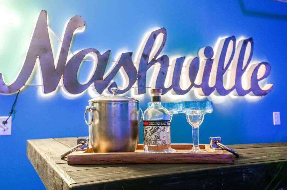 Nashville neon sign glowing over the bar with drinks ready, this is where the night gets good