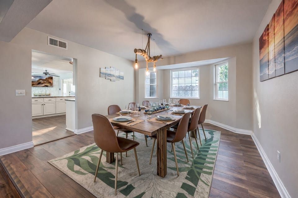 Sunlit dining room for 8 with rustic table, chic lighting, hardwoods