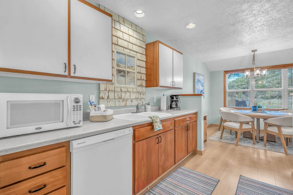 Your fully equipped kitchen awaits with warm wood cabinets, modern appliances, and charming brick backsplash, perfect for cooking memorable meals.