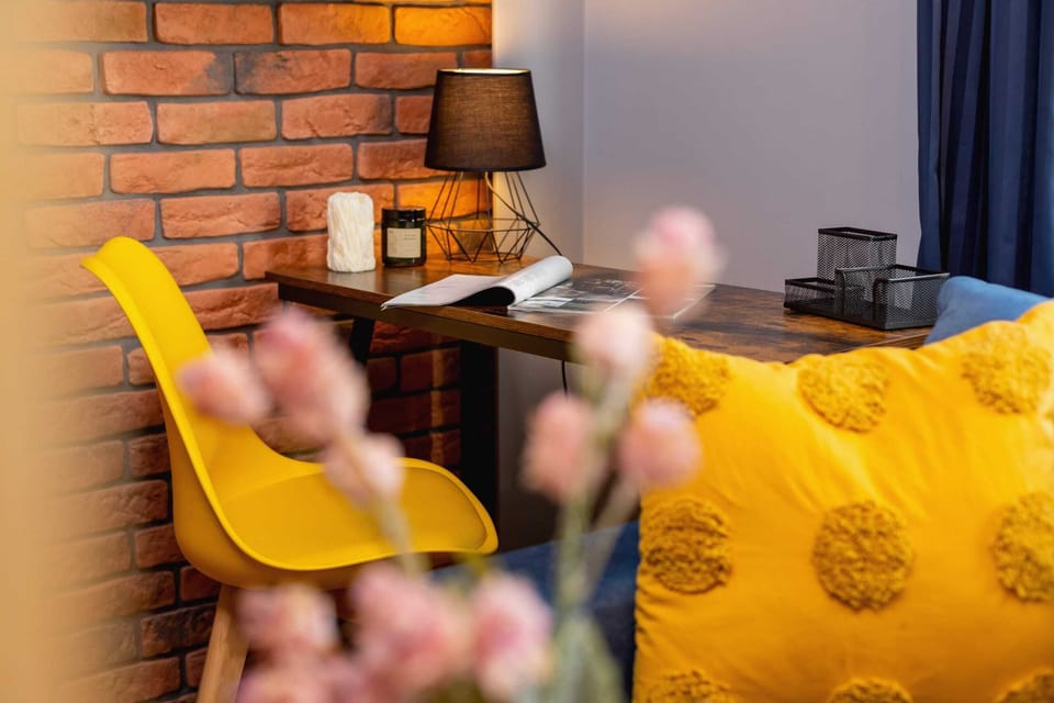 A decorative yellow chair and lamp against a brick wall, adding a vibrant and stylish touch to the space.
