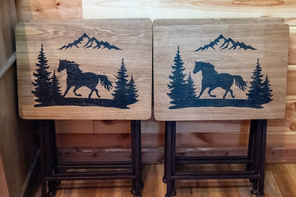 - Wooden horse patterned tables with mountain art   - Rustic decor piece enhancing cabin character   - Cozy forest cabin detail perfect for warm stays retreat forest cabin