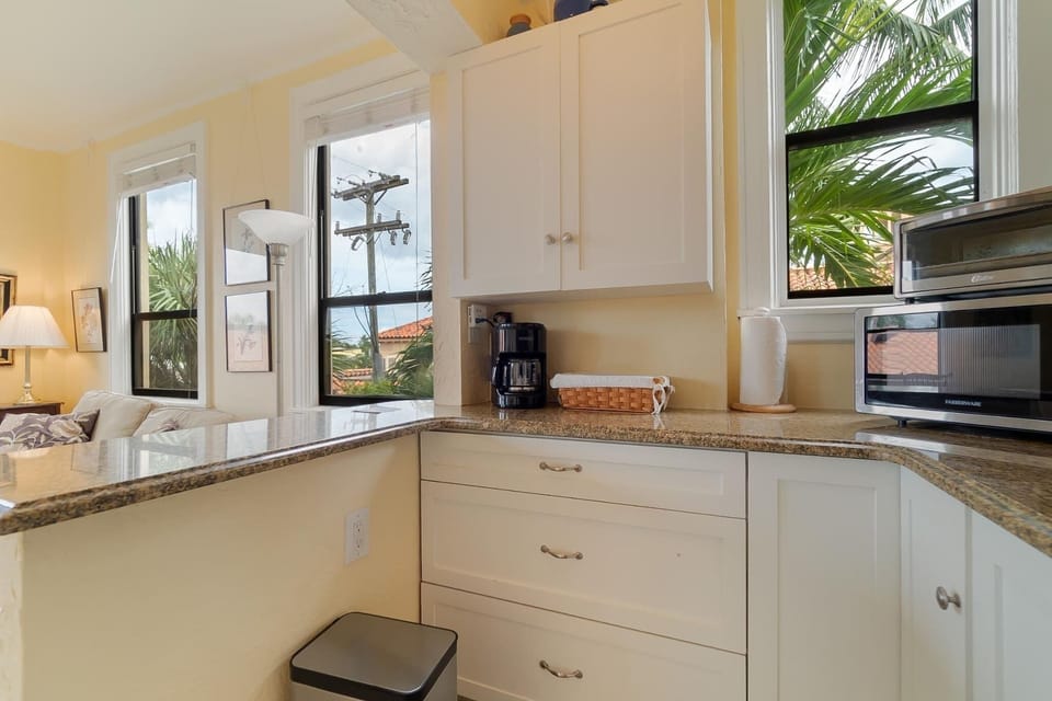 Kitchenette with a Toaster oven, microwave, mini fridge, Keurig coffee maker, glasses, plates, and cutlery. 
