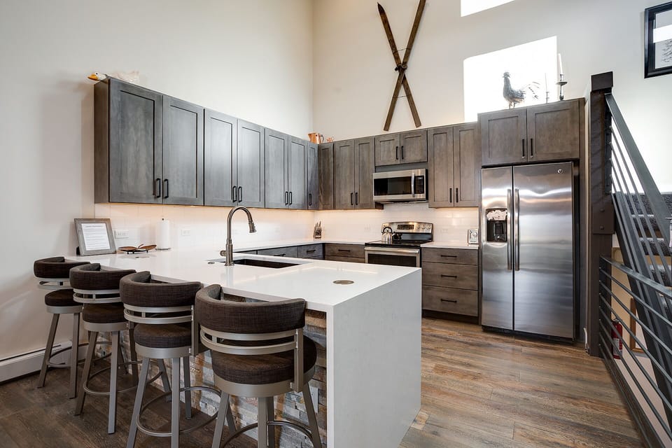 Your modern kitchen awaits with sleek stainless appliances, spacious quartz island, and warm wood cabinetry perfect for morning coffee or evening meals together.