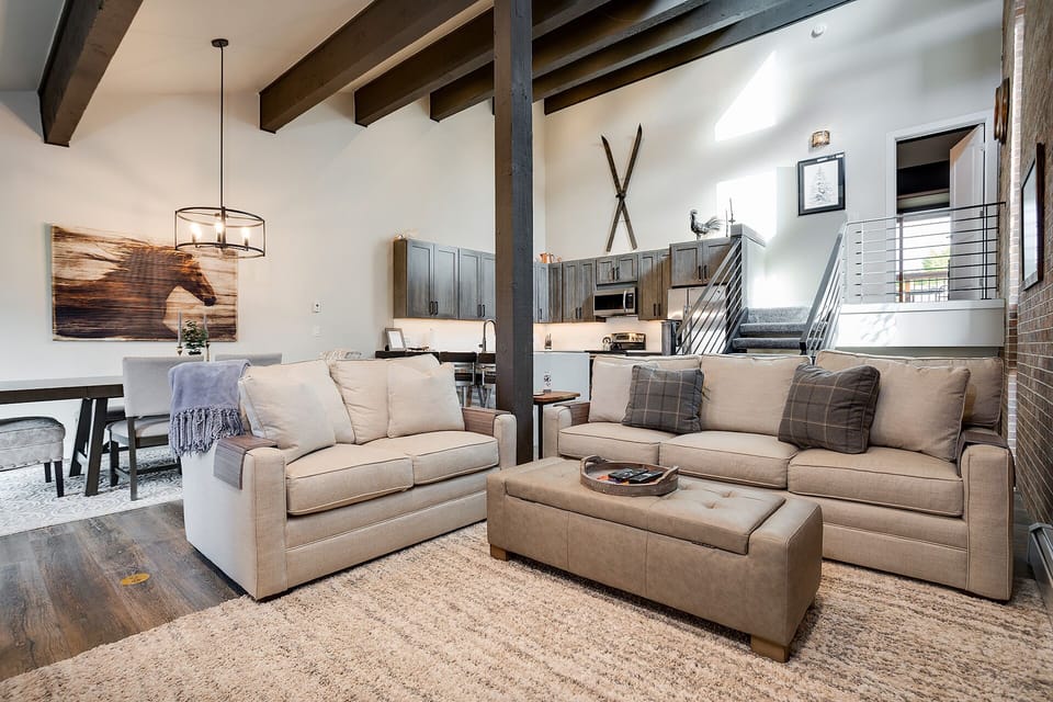 Sink into plush sofas beneath rustic beams in this open-concept retreat, where modern mountain style meets cozy comfort for your perfect getaway.