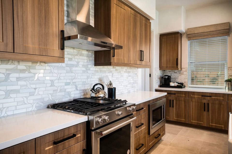 Warm wood cabinetry, gas cooktop & tiled backsplash for a polished kitchen look